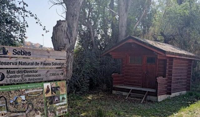 Muestra el nombre de la Reserva natural de Sebes en un rótulo de madera al lado de una cabaña